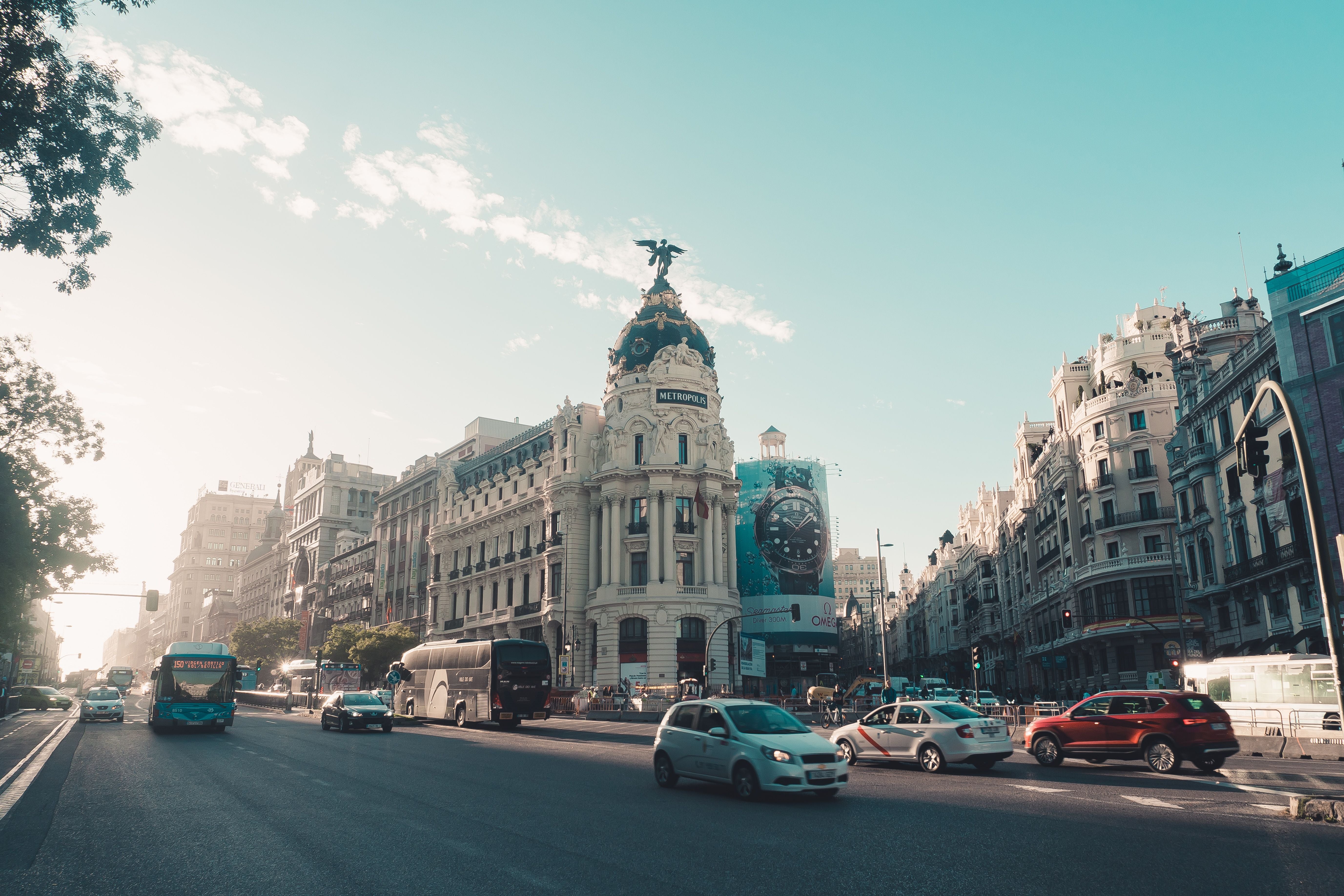 Madrid street with traffic and historic buildings under a clear blue sky.