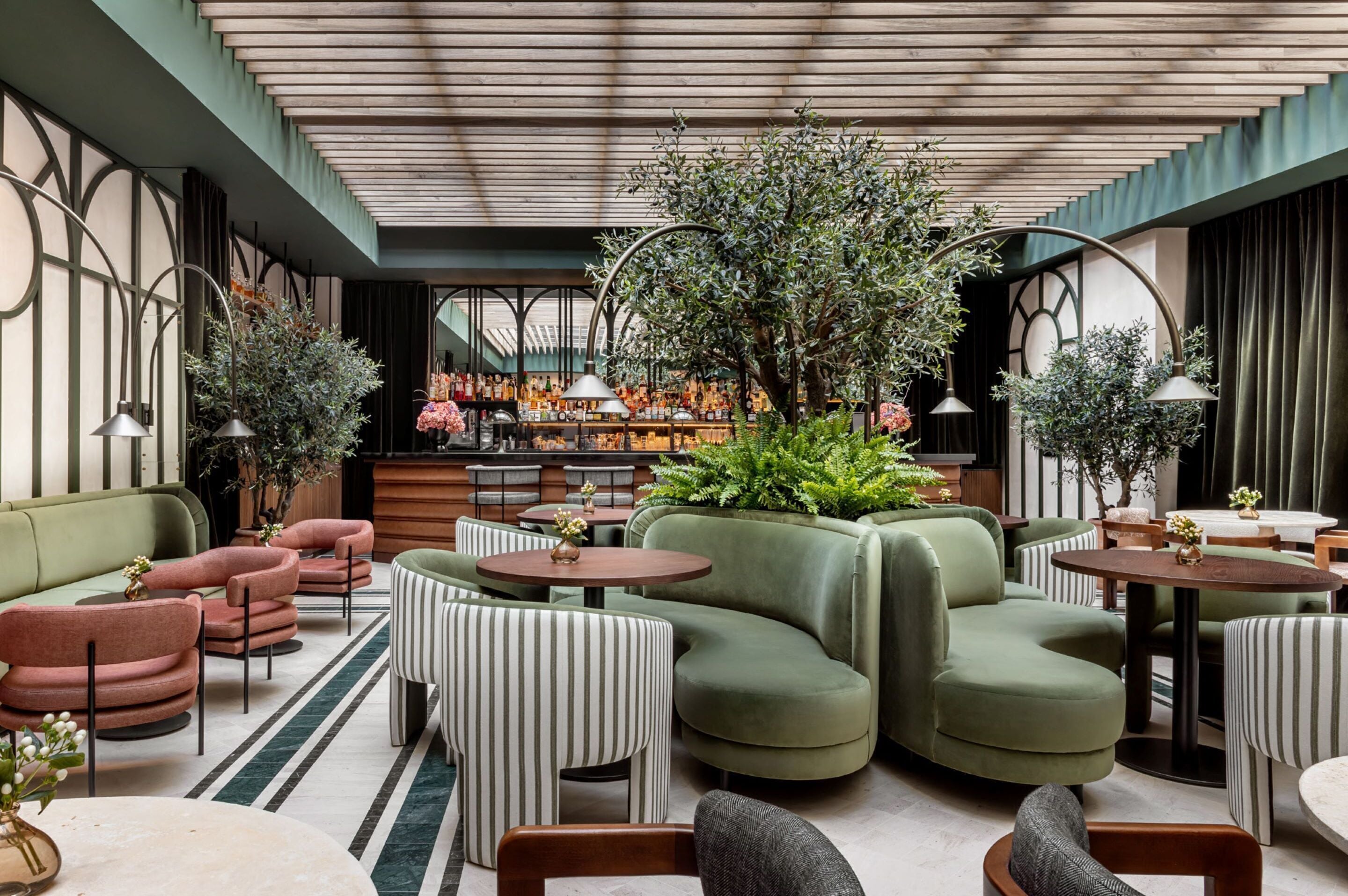 Hotel Totem Madrid's Modern interior with green and pink furniture, plants, and a bar area.